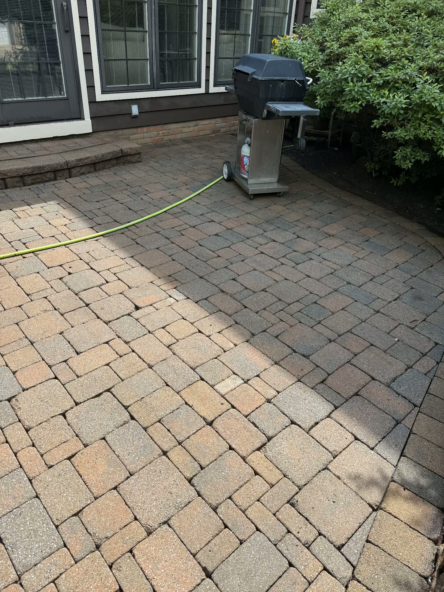 Paver patio mid-clean with a sharp line between dirty and clean