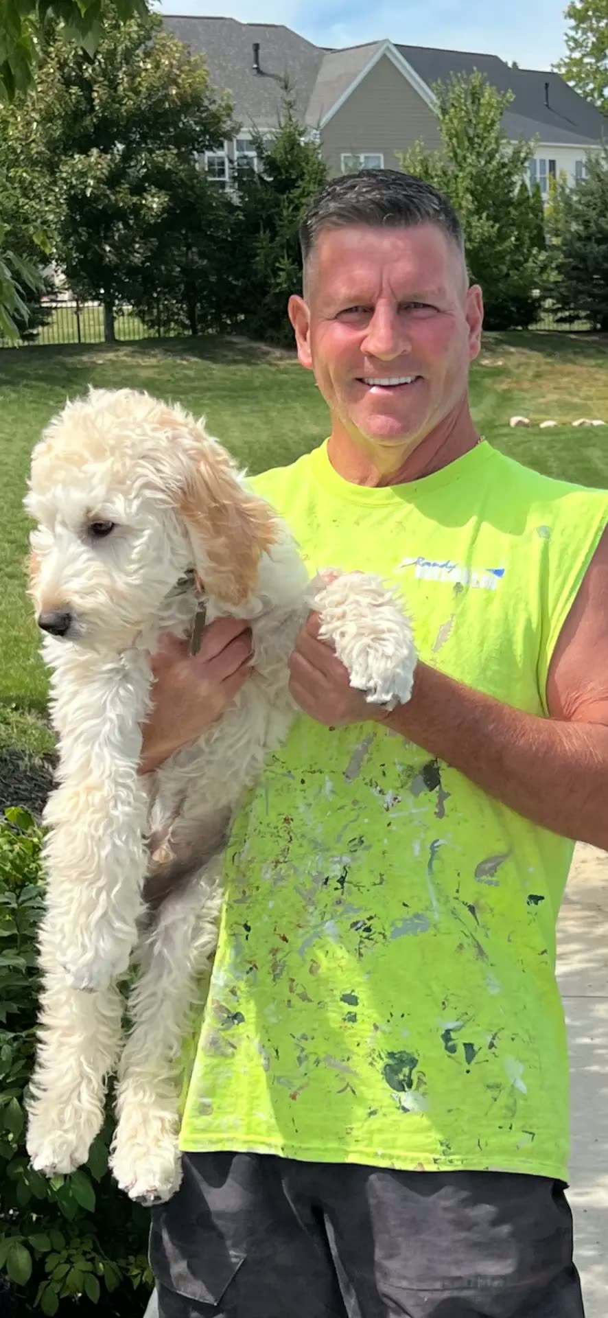 Randy Wilhelm in his work shirt holding a puppy on a job site
